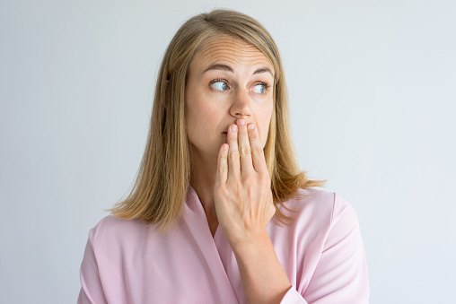 Woman with bad breath holding her mouth with one hand