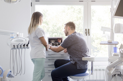 dental staff in office in front of monitors discuss digital image
