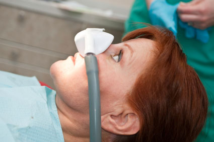 Woman laying down in dental chair getting laughing gas